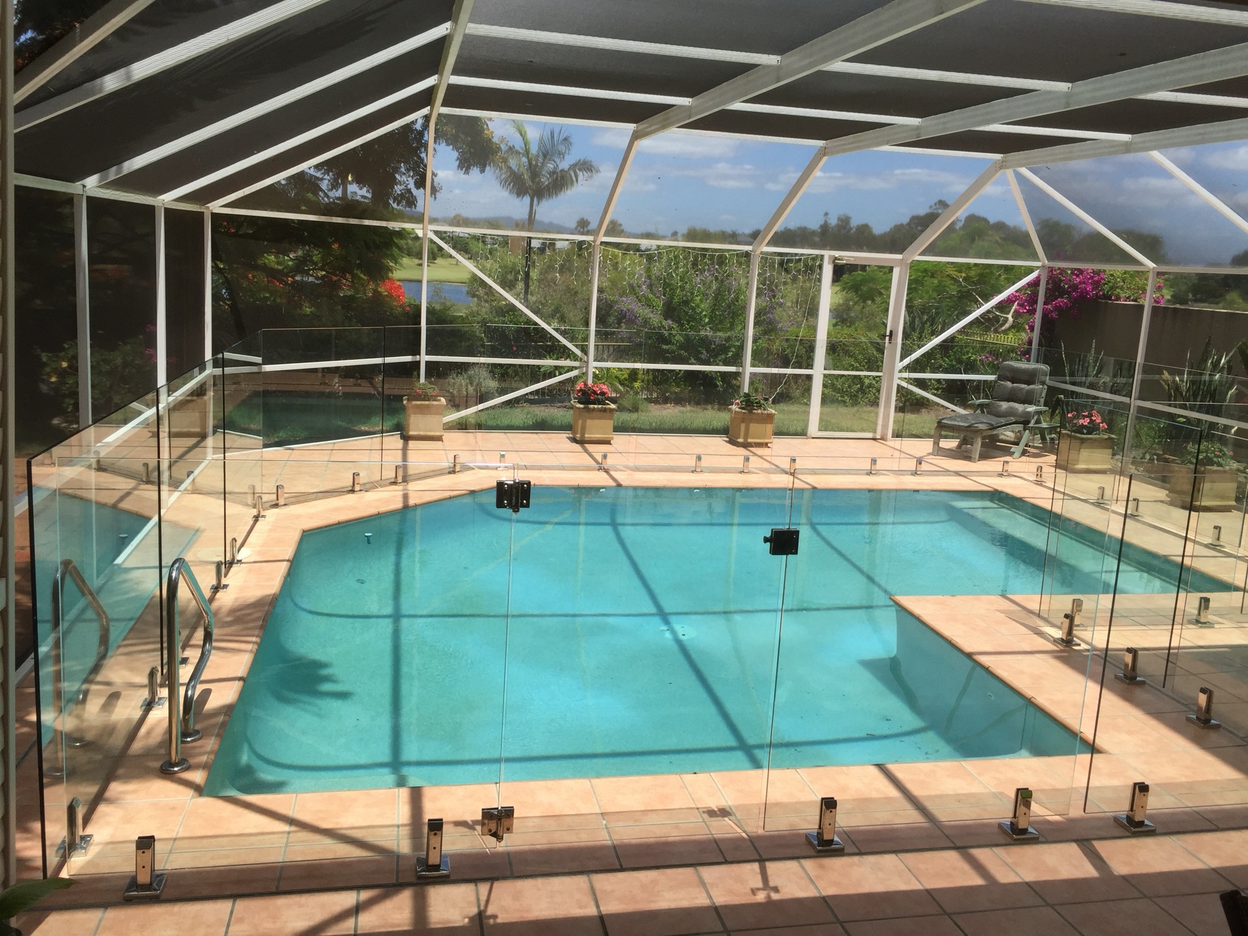 Frameless glass pool fencing with polished stainless spigots around a resort-style pool